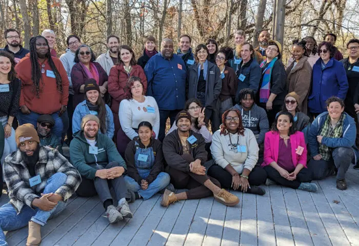 Members of the staff, Board, and Southwest Philadelphia Community Leadership Team stand and sit outside on a sunny autumn day.